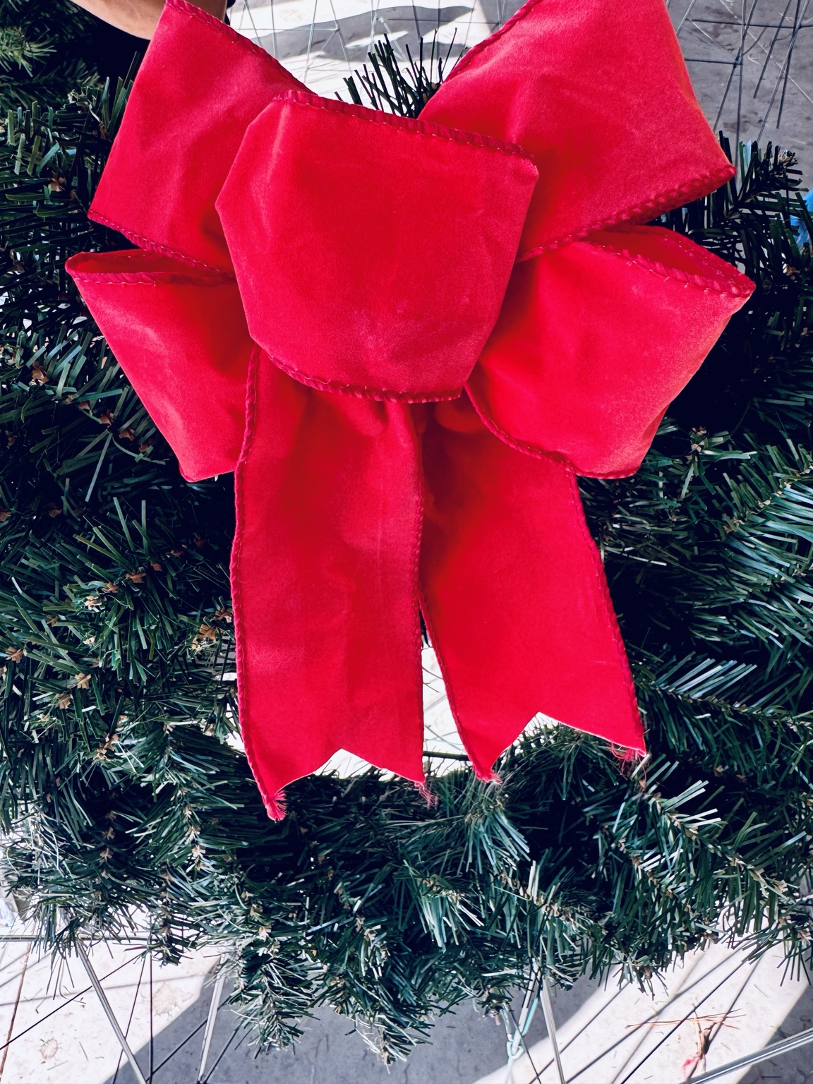 A reusable green veterans’ wreath finished with a bright red fabric bow.